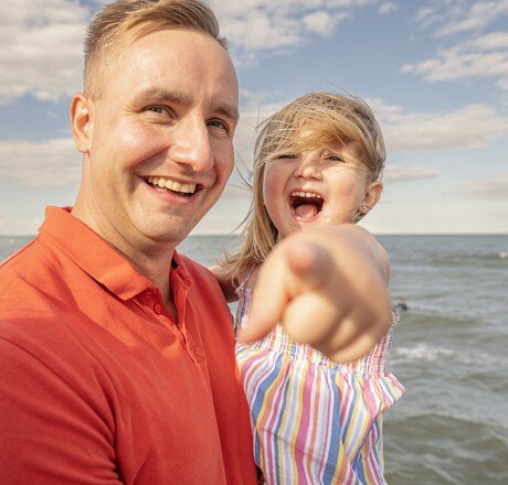 Mann mit Kind lachend stehen vor dem Meer