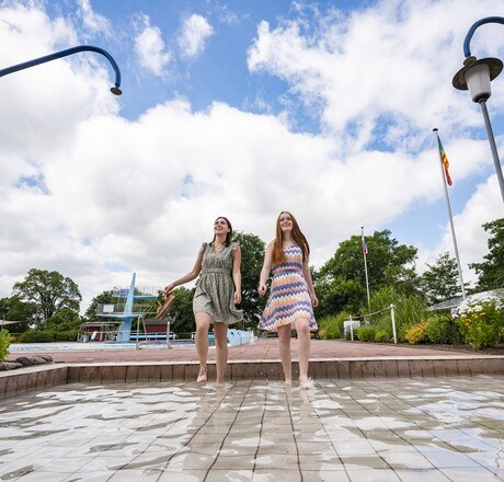 Zwei junge Frauen kühlen sich die Füße am Springbrunnen